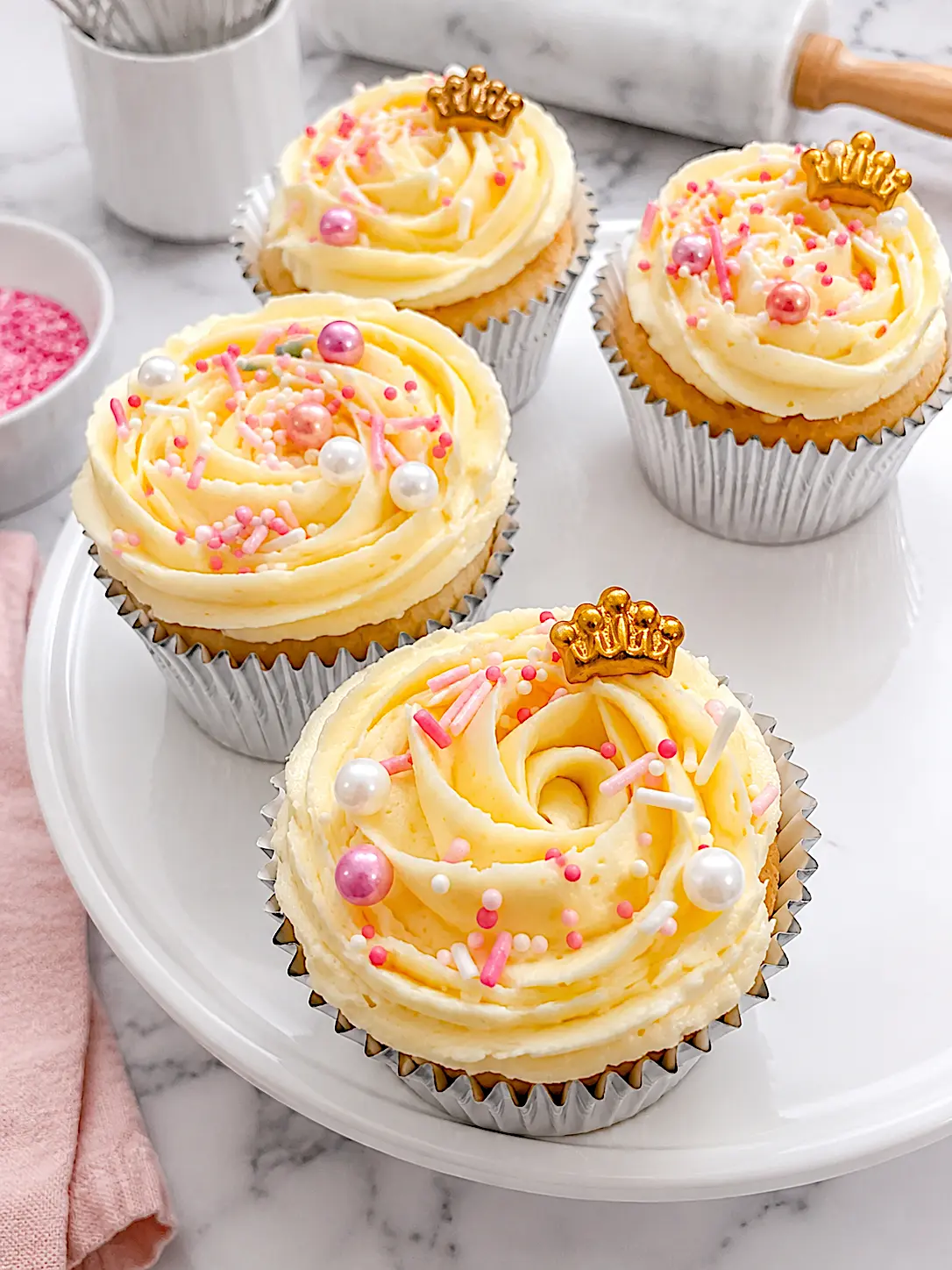 Vanilla cupcakes with gold crowns, sprinkles and pearls
