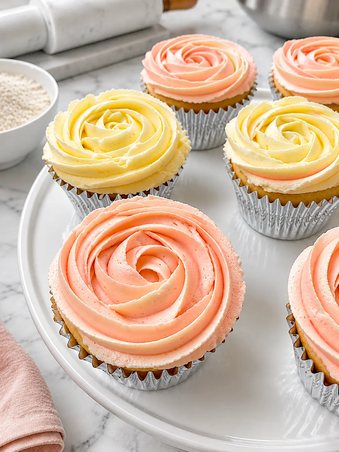 Pastel rosette-piped cupcakes on a white cake stand